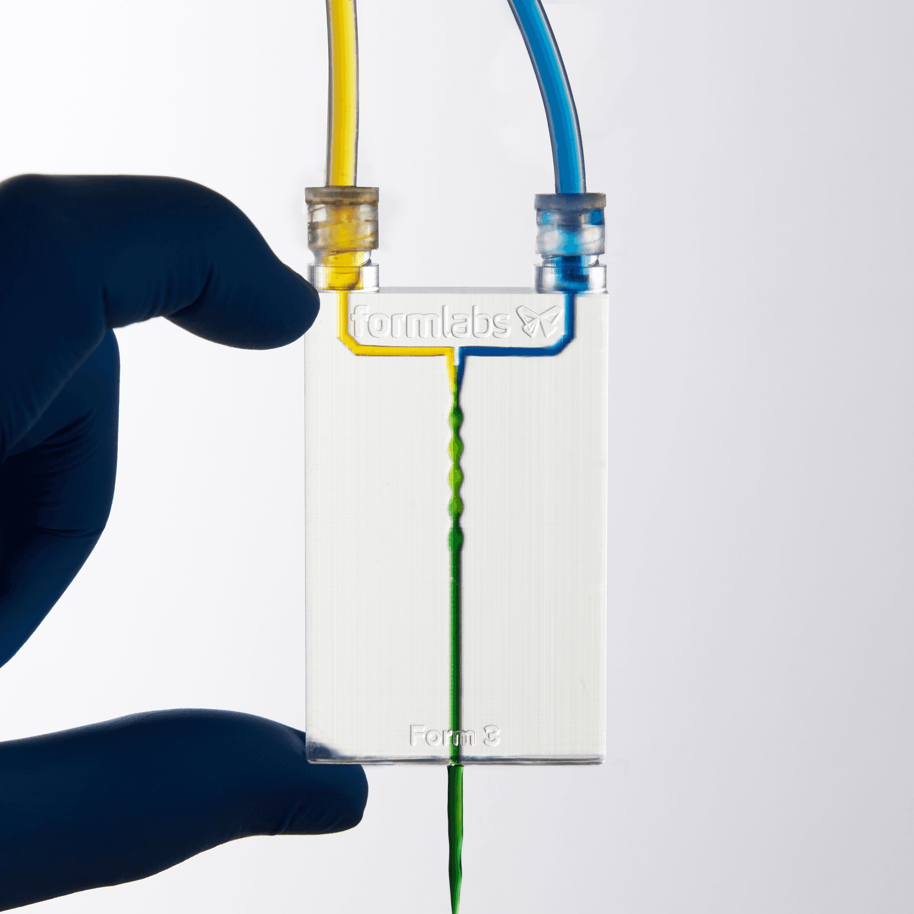 具有 3D 通道的透明设备。黄色液体从左上方注入,蓝色液体从右上方注入,混合后形成绿色液体