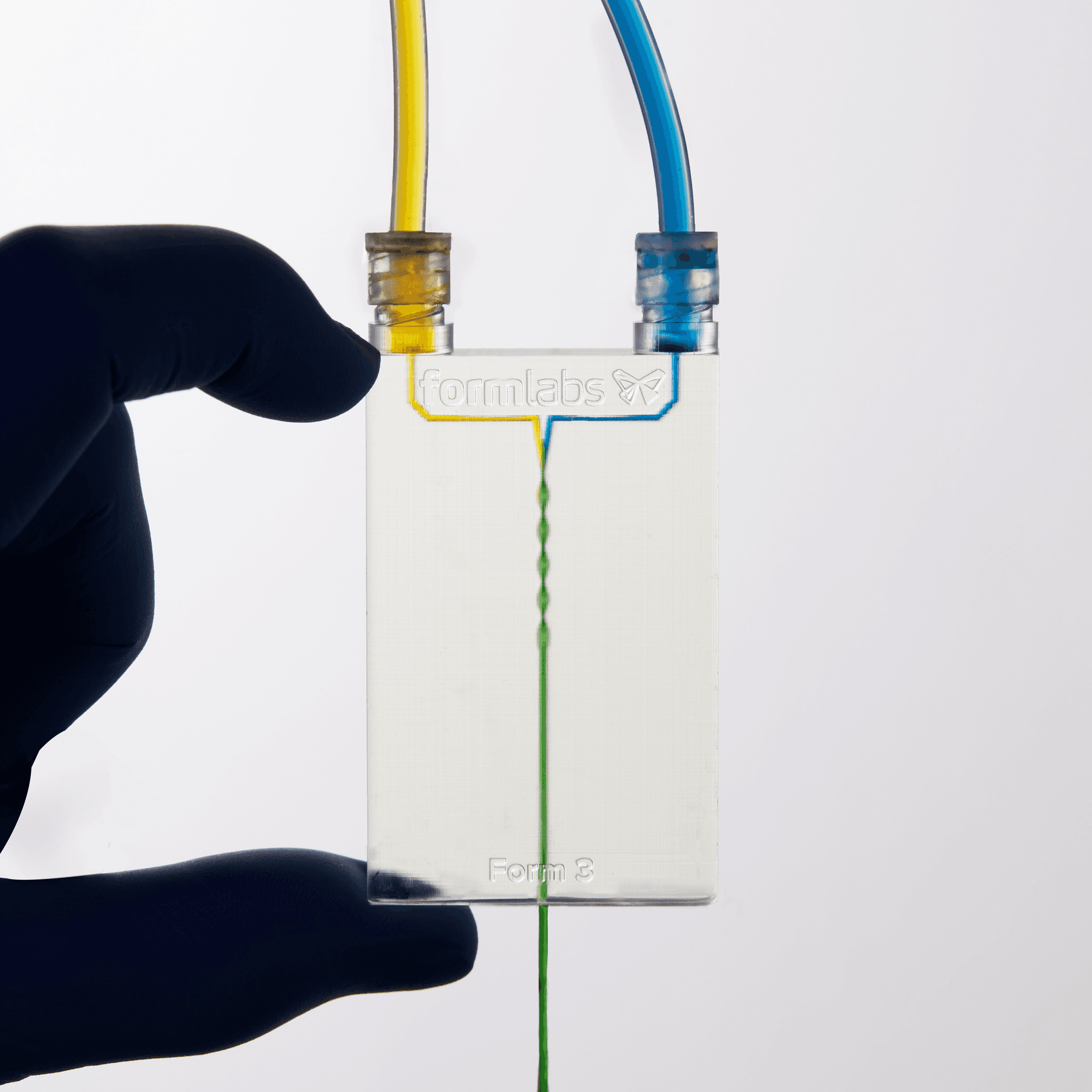 具有 3D 通道的透明设备。黄色液体从左上方注入,蓝色液体从右上方注入,混合后形成绿色液体