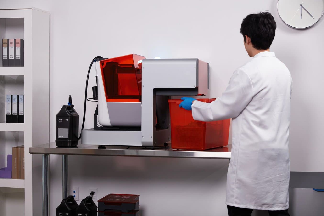 一名身穿白大褂的男子正在从 Form Auto 上取下部件,其后部插有 Resin Pumping System