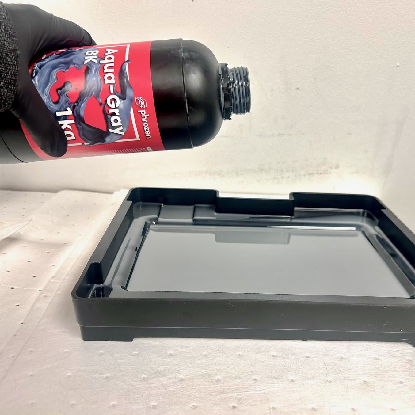 戴着手套的手正在将树脂倒入树脂槽中