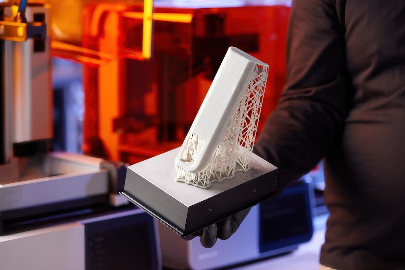 一名人员手持一个带有 3D 打印塔的构建平台